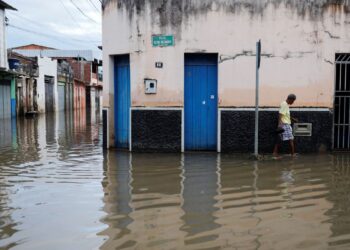 A person walks through the water along a street during floods caused by heavy rain in Itajuipe, Bahia state, Brazil December 27, 2021. REUTERS/Amanda Perobelli