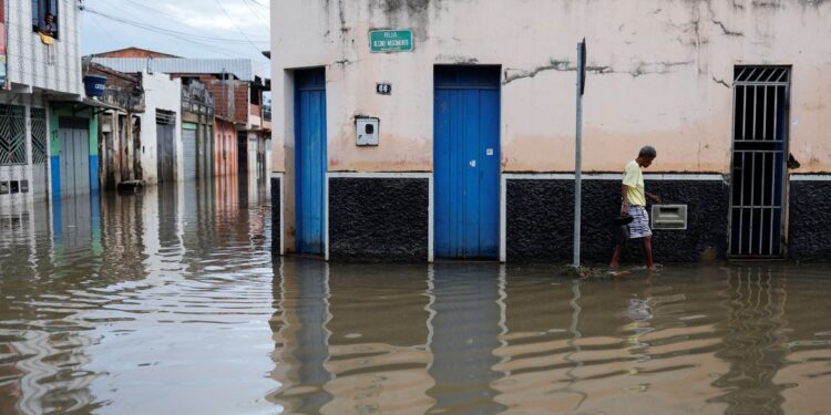 A person walks through the water along a street during floods caused by heavy rain in Itajuipe, Bahia state, Brazil December 27, 2021. REUTERS/Amanda Perobelli